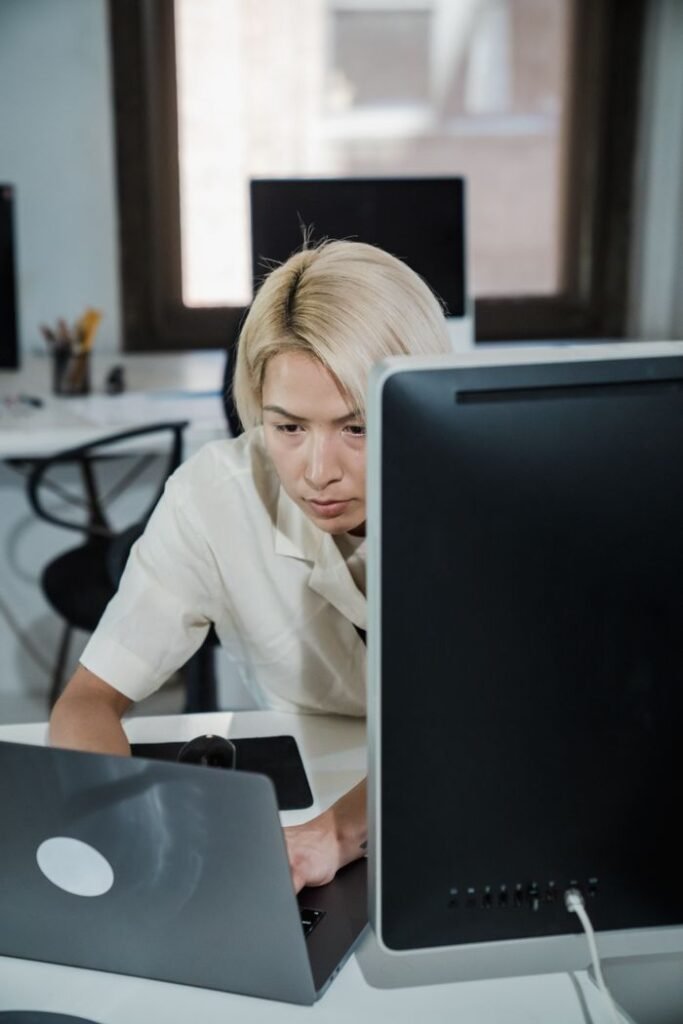 pexels-photo-12899190-12899190 Focused office worker with blonde hair working diligently at a computer desk in modern office.